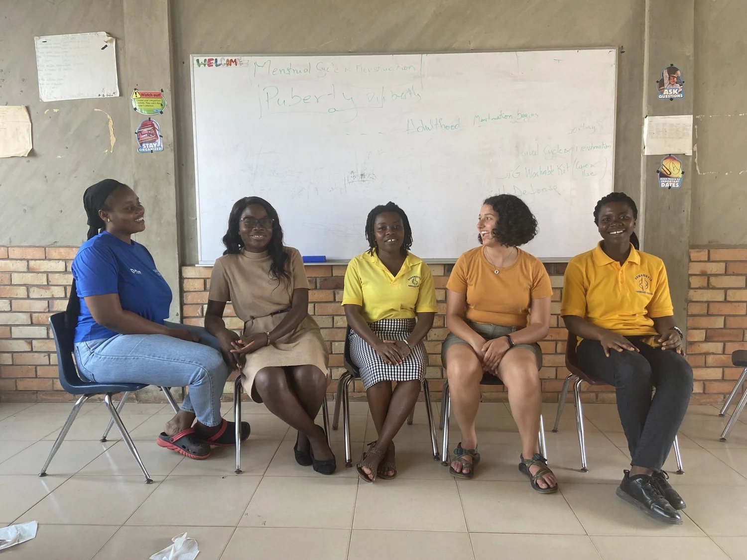 Five women from the Senase project team seated in front of a whiteboard about puberty and menstruation